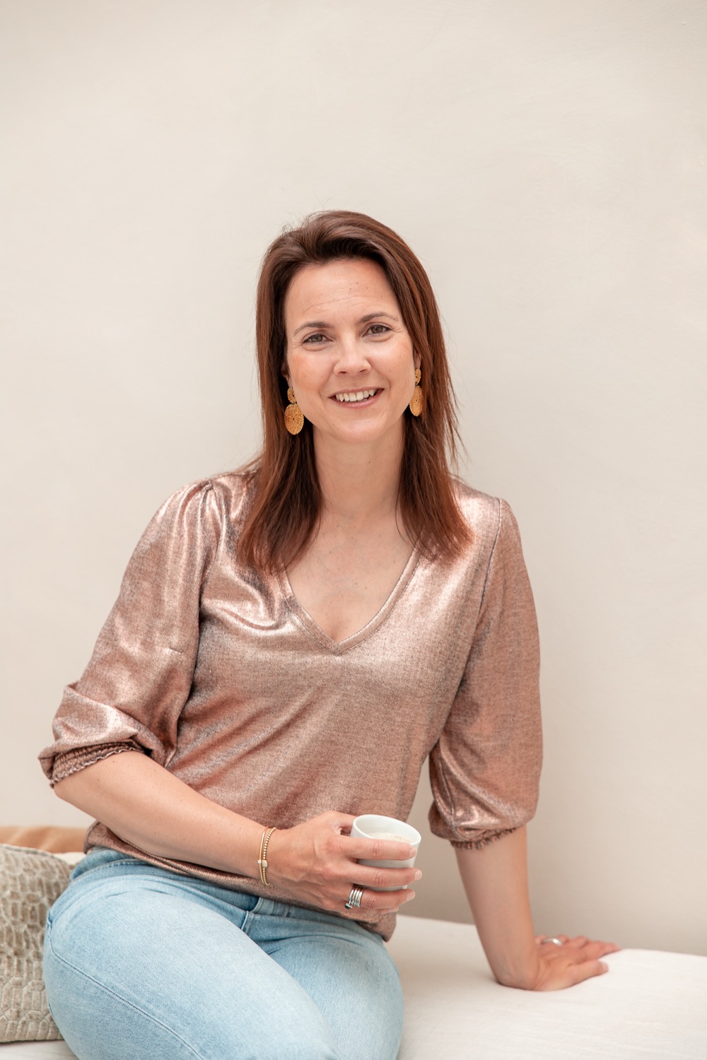 Monique Vekemans glimlacht rustig, met een kop koffie in haar hand